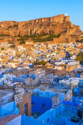The blue city of Jodhpur with Mehrangarh Fort in the background at sunset.