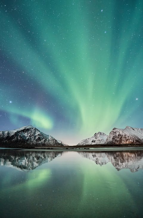 Aurora borealis in Norway overlooking mountains and lake