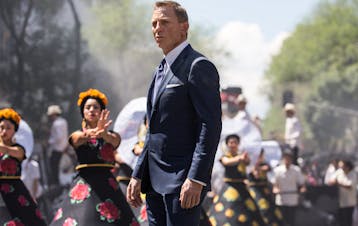 Bond (Daniel Craig) following Marco Sciarra through the Day of the Dead parade; Tolsa Square, Mexico City, Black Tomato